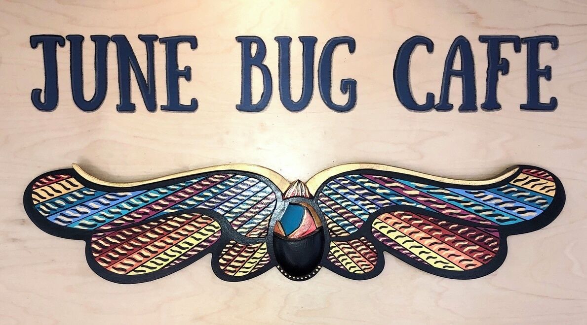 A wall with the text "JUNE BUG CAFE" and a colorful butterfly decoration.
