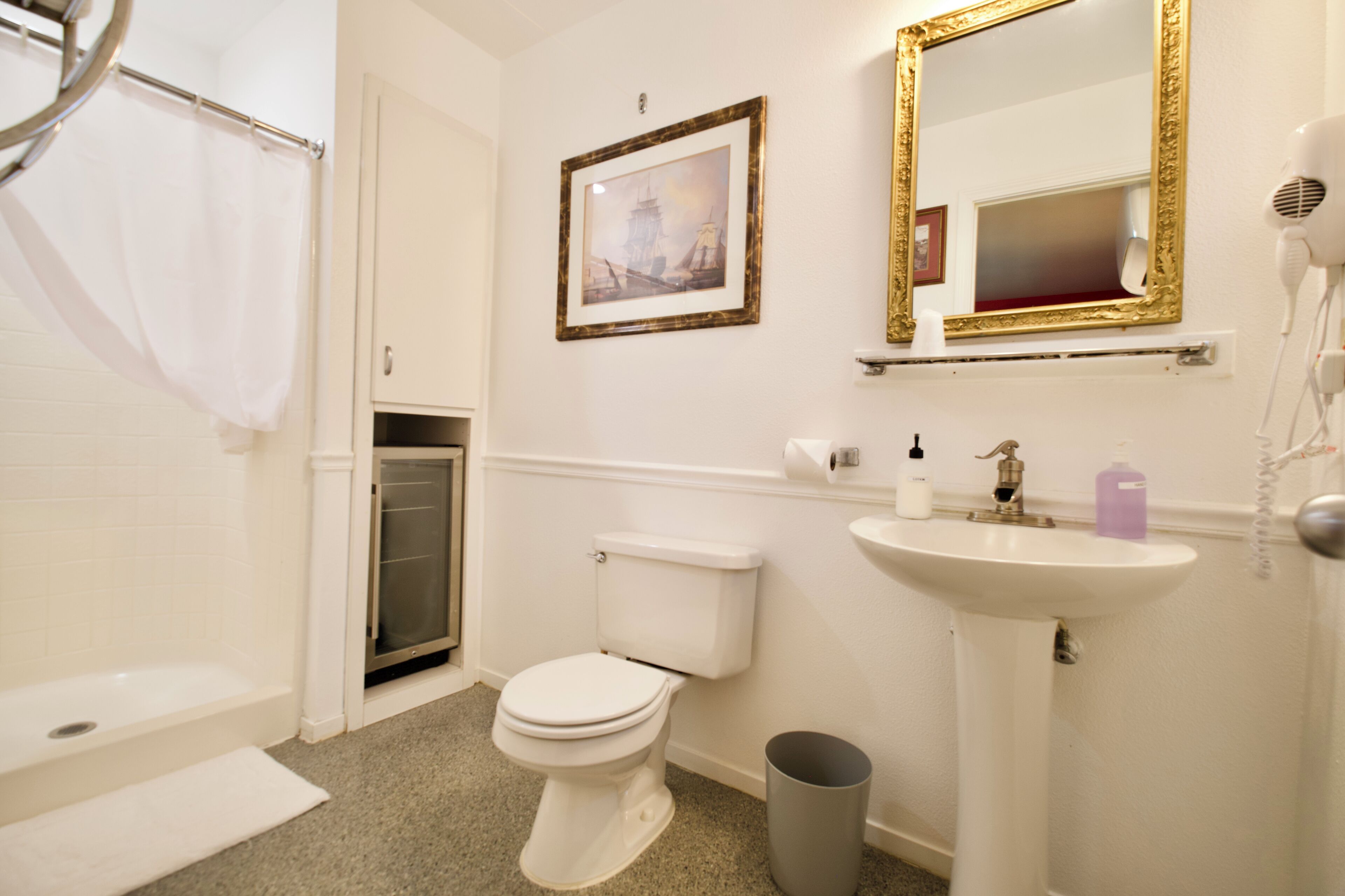 A bathroom with a toilet, sink, and a framed picture on the wall.