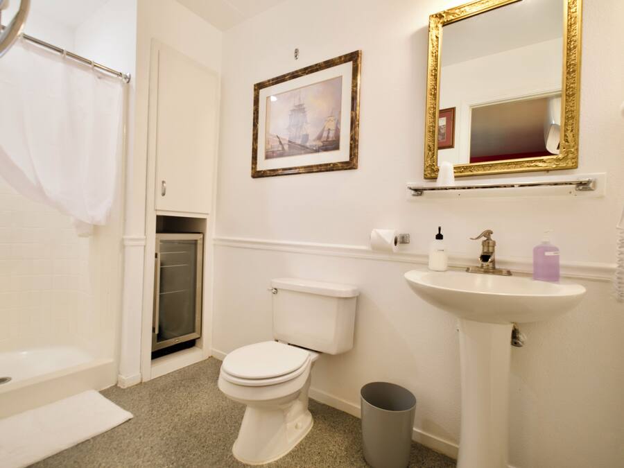 A bathroom with a toilet, sink, and a framed picture on the wall.