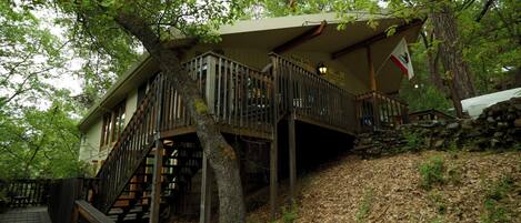 A cabin with a wooden deck, a staircase, and a sign for a health spa and cafe.