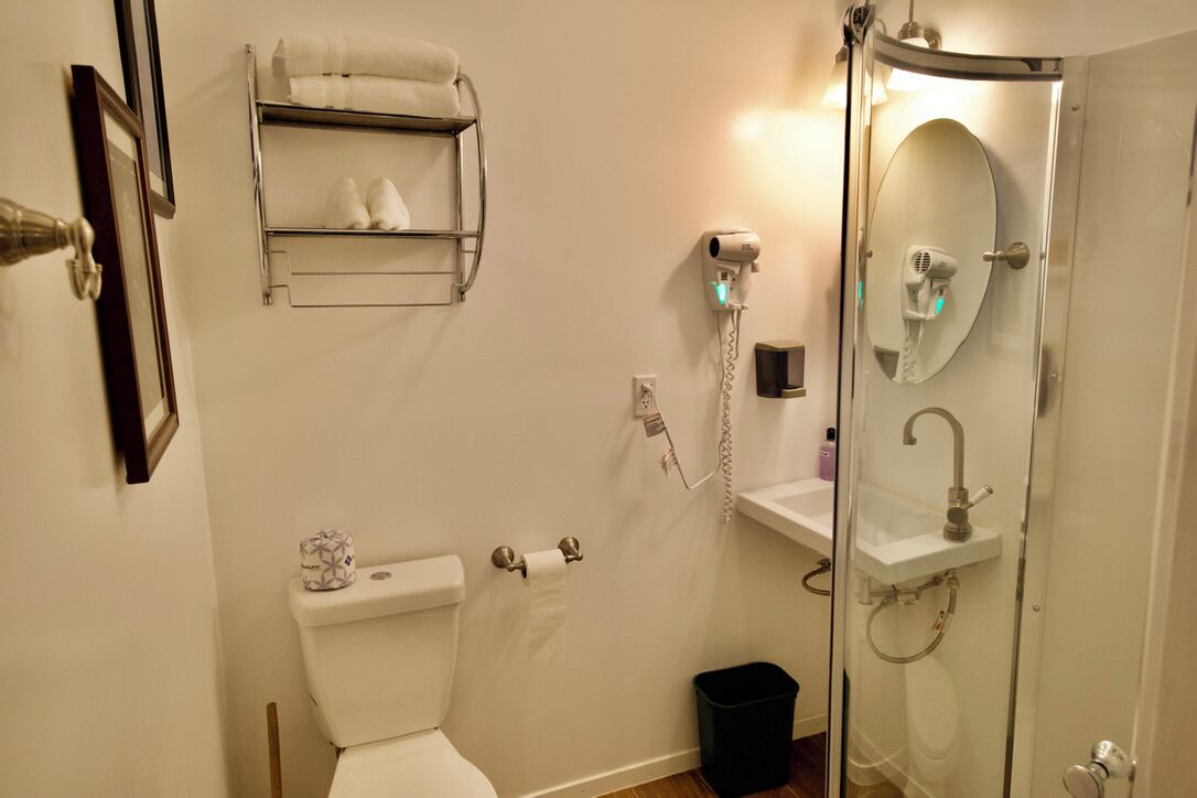 A bathroom with a toilet, a towel rack, a shower with a glass door, and a sink.