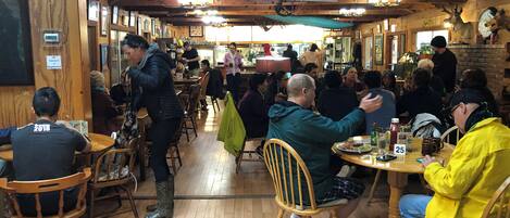 A restaurant with wooden interiors, multiple tables, and chairs.