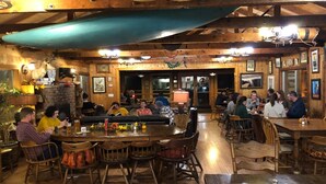 A rustic wooden interior with a bar area, wooden tables, and chairs. - Yosemite Bug Rustic Mountain Resort (Midpines)