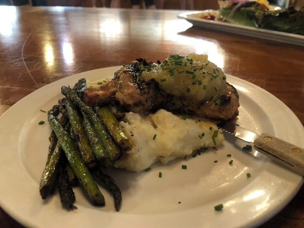 Une assiette contenant du poulet grillé, de la purée de pommes de terre et des asperges, posée sur une table en bois.
