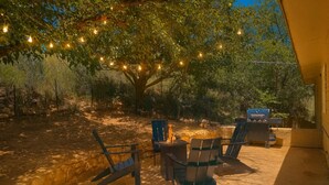 An outdoor patio with a barbecue grill, two chairs, and string lights. - Brookhollow Escape at Ransom Canyon (Ransom Canyon)