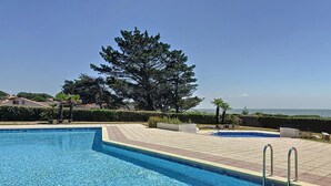 Una piscina cristallina blu con bordo piastrellato e scaletta in metallo.