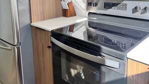 Eine Küche mit einem Edelstahl-Kühlschrank, einer Mikrowelle, einem Backofen und einem Kochfeld.