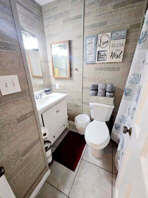 Une salle de bain avec un lavabo blanc, un miroir, des toilettes et des panneaux décoratifs sur les murs.