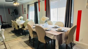 A dining area with a table set for four, chairs, a ceiling fan, and a window with curtains. - Charming 3-bedroom house with an outdoor pool, WiFi, &AC in phenomenal Las Vegas (Las Vegas)