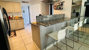 A modern kitchen with a granite countertop, white bar stools, and a built-in oven. - Charming 3-bedroom house with an outdoor pool, WiFi, &AC in phenomenal Las Vegas (Las Vegas)