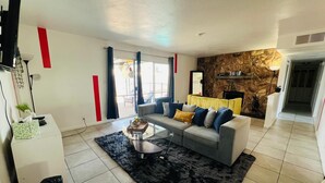 A modern living room with a grey sofa, black and white rug, and a stone wall. - Charming 3-bedroom house with an outdoor pool, WiFi, &AC in phenomenal Las Vegas (Las Vegas)