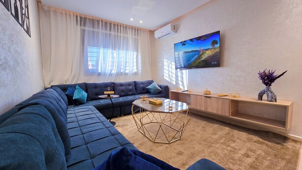 Una sala de estar moderna con un sofá seccional, una mesa de centro y un televisor montado en la pared.