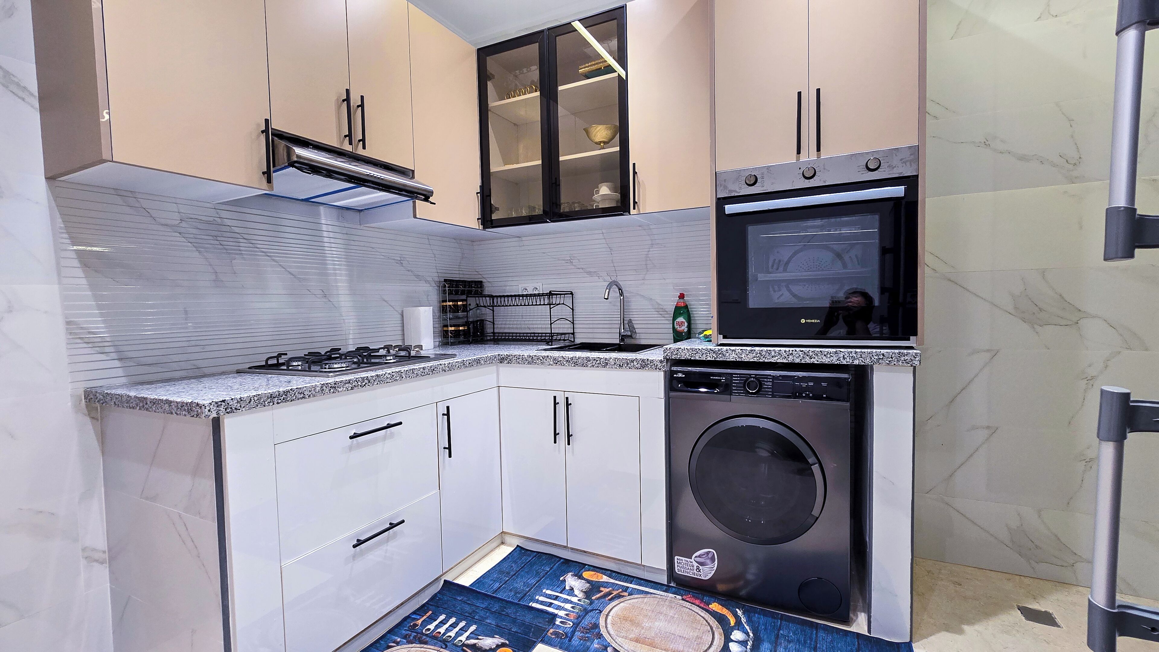 A compact kitchen with a built-in oven, microwave, and washing machine.