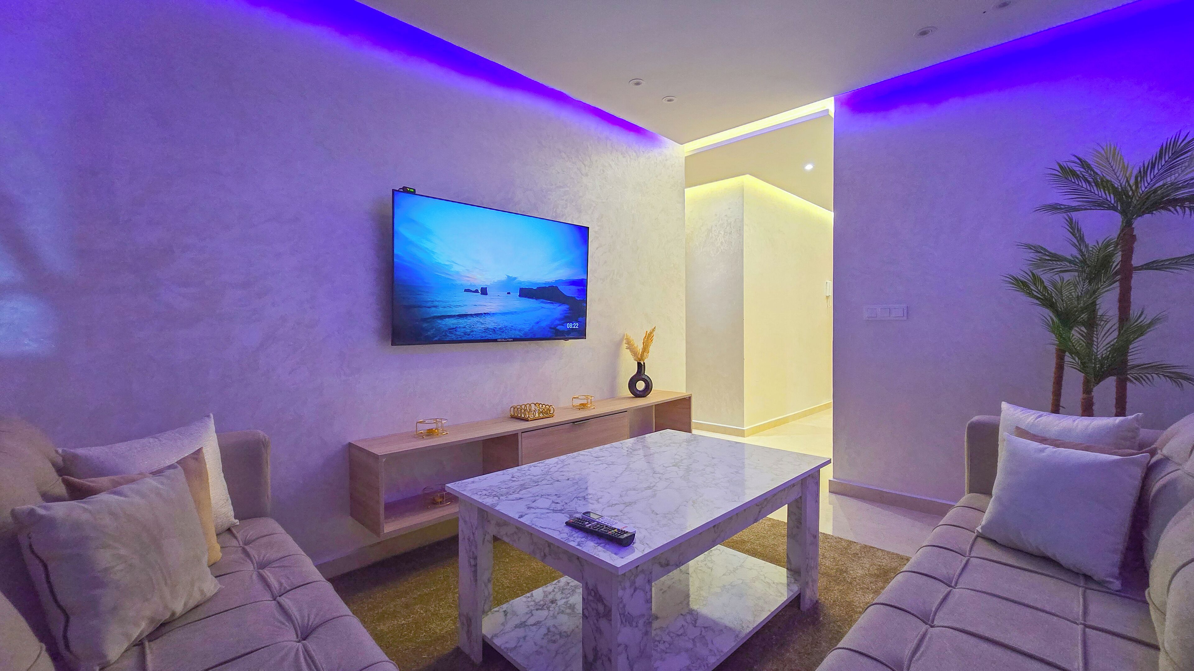 Una sala de estar moderna con un televisor de pantalla plana, una mesa de centro de mármol y un sofá.