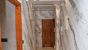 A hallway with marble walls, a wooden door, and recessed lighting.