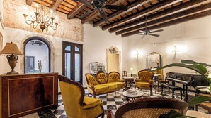 A spacious living room with a checkered floor, a piano, and a chandelier. - Casa Lucienne - Adults Only (San Juan)