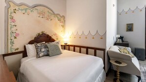 A bedroom with a bed, a chair, a lamp, and a wall with a floral design. - Casa Lucienne - Adults Only (San Juan)