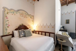 Un dormitorio con una cama, una silla, una lámpara y una pared con diseño floral.