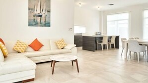 Ein modernes Wohnzimmer mit einer Couch, einem Couchtisch und einem Gemälde mit Segelbooten.