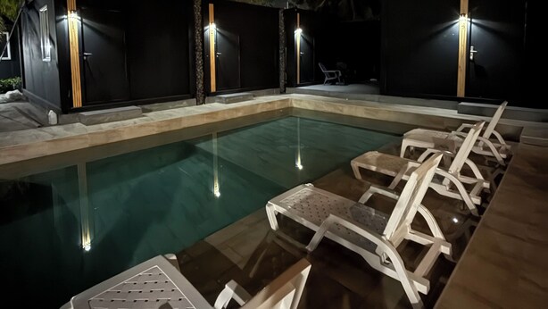 Una piscina con sillas de descanso y una terraza de madera.