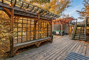 A wooden deck with a pergola and a bench, surrounded by autumn foliage. - 15 min to Gonzaga · Speakeasy · Pets welcome (Spokane)