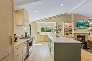 A modern kitchen with a central island, built-in appliances, and a large window.