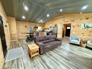 Ein gemütliches Blockhaus-Interieur mit einer Holzeinrichtung, einer Küchenzeile, einer Couch und einem kleinen Tisch.