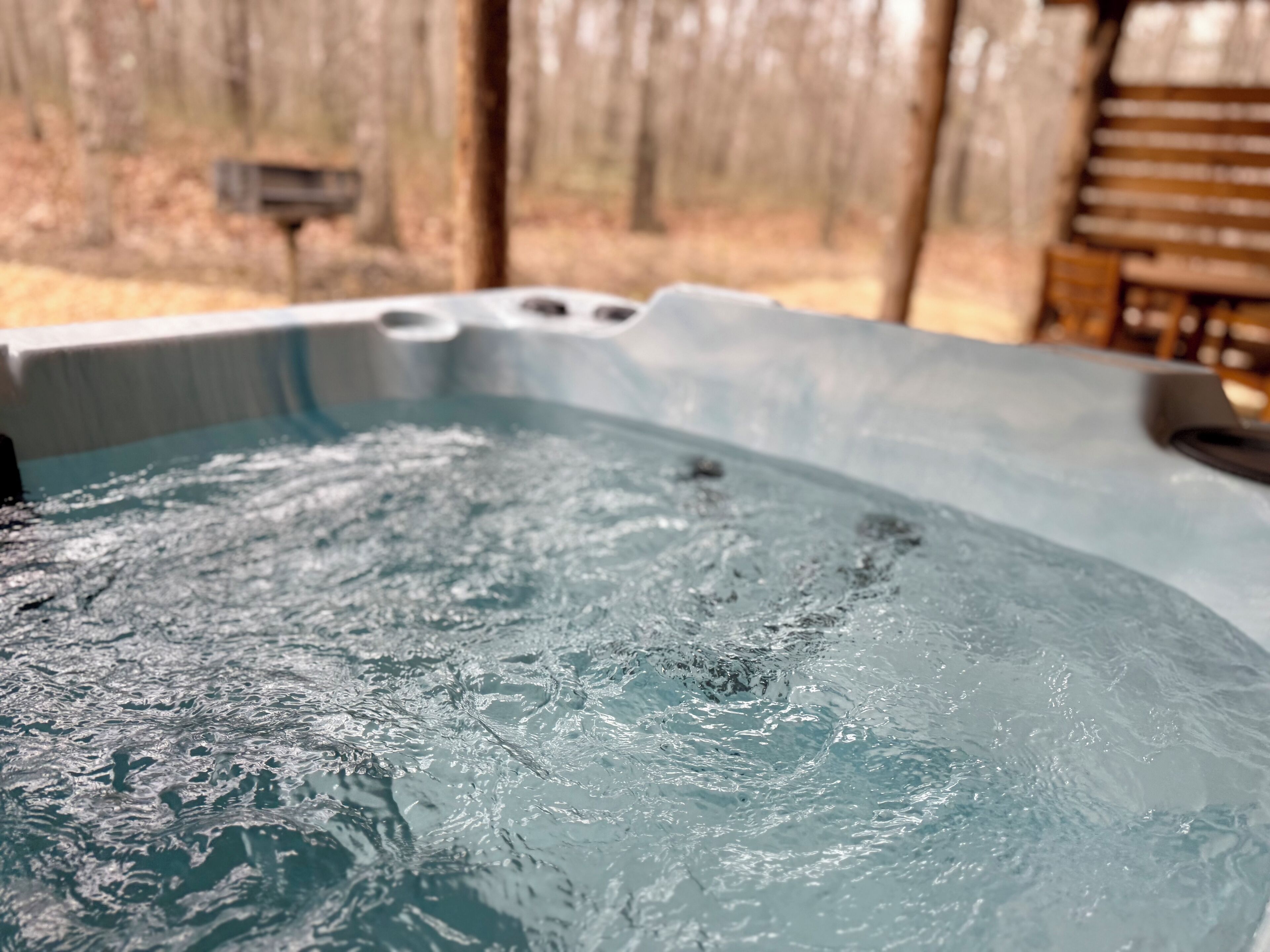 A hot tub with water, a wooden wall, and a chair in the background.