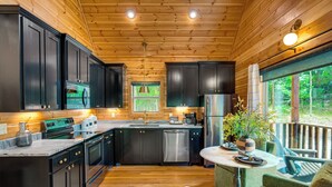 A modern kitchen with dark cabinets, stainless steel appliances, and a wooden ceiling.