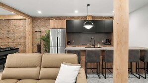 Una cocina moderna con pared de ladrillo, electrodomésticos de acero inoxidable y una lámpara colgante.