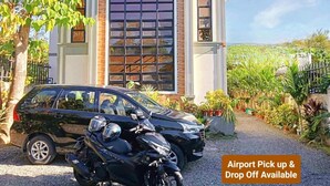 A house with a garage, a driveway, and a motorcycle parked in front. - Charming Bed & Breakfast Room #1 with WiFi and AC in Delightful Compostela Cebu (Compostela)