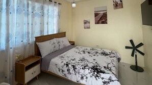 A bedroom with a bed, bedside table, and a ceiling light fixture. - Charming Bed & Breakfast Room #1 with WiFi and AC in Delightful Compostela Cebu (Compostela)