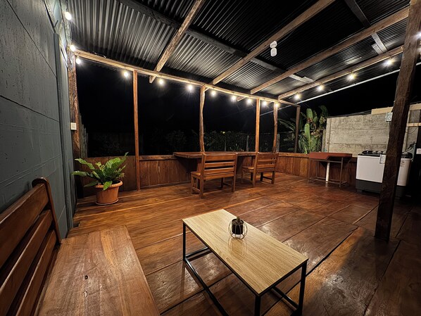 An outdoor patio with wooden furniture, string lights, and a table.