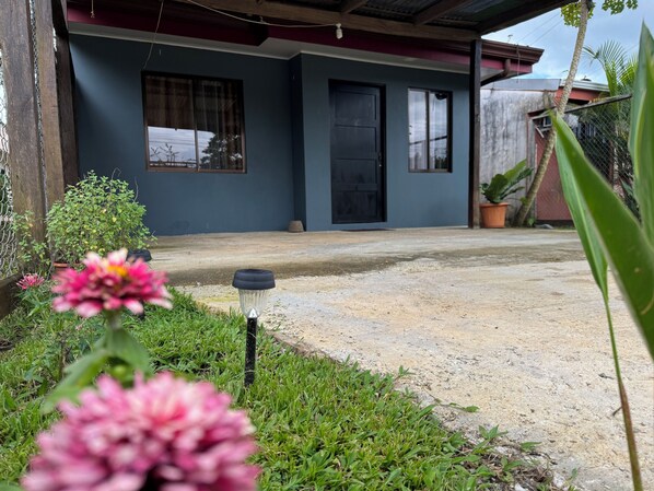 A house with a concrete porch, a black door, and a window with a curtain.