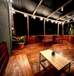 An outdoor patio with wooden furniture, a table, and potted plants.