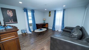 A living room with a sofa, a wooden coffee table, a desk, and a chair. - Charming 3-bedroom apartment with WiFi, AC in lovely Leominster (Leominster)
