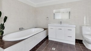 Un bany modern amb una banyera autònoma, un lavabo blanc amb calaixos i un vàter.