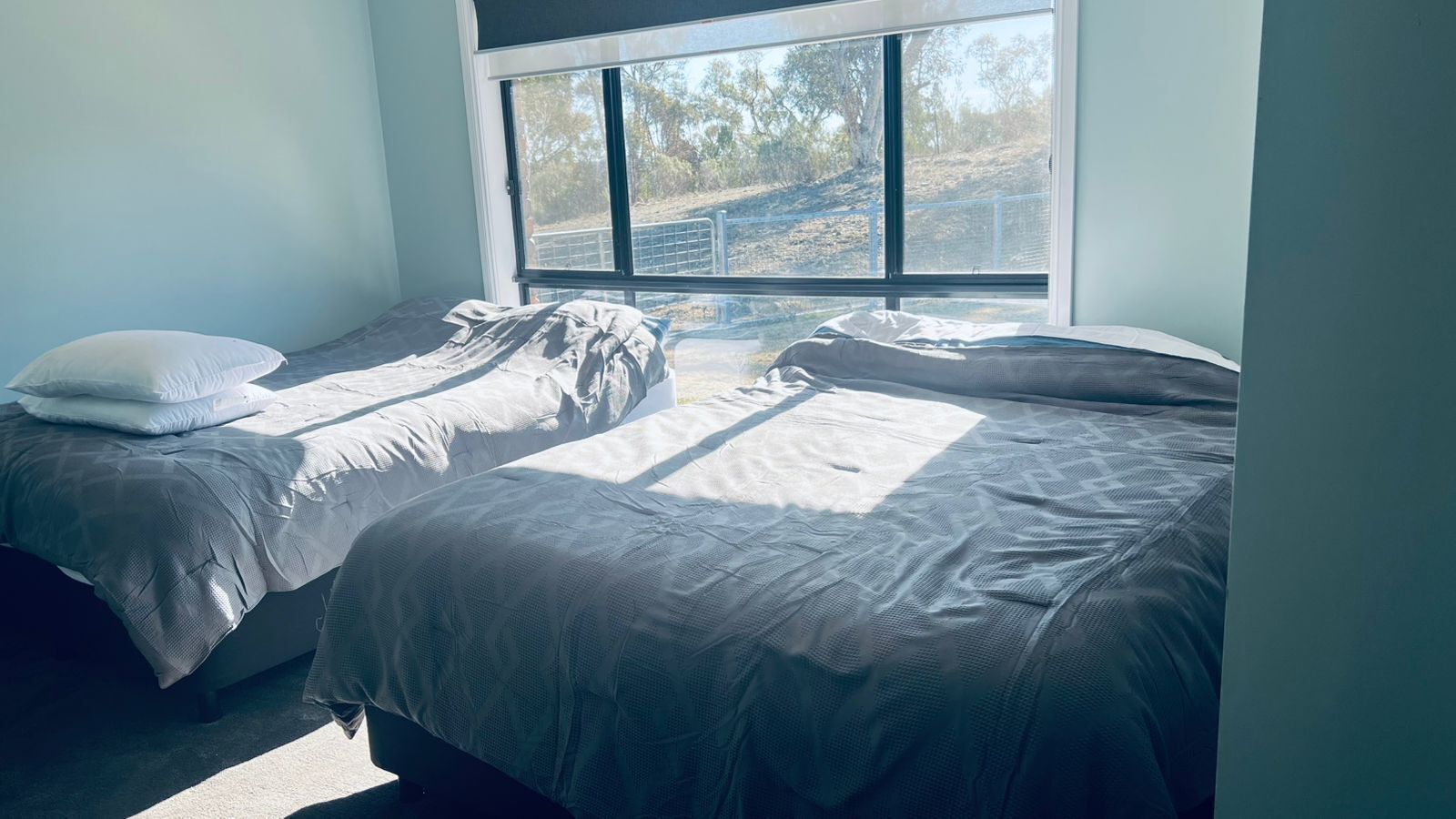 A bedroom with two beds, a large window, and a view of the outdoors.