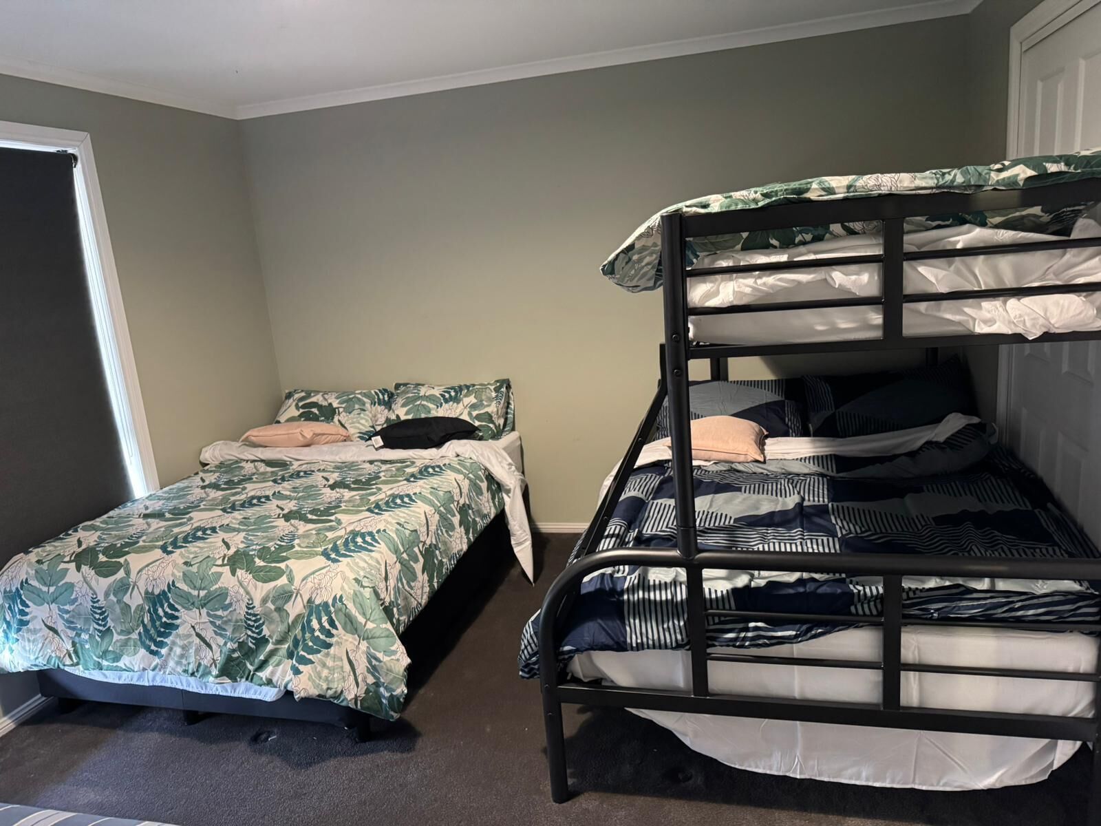 A room with a bunk bed and a single bed, both with patterned bedding.