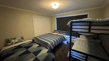 Habitación tipo dormitorio con dos camas individuales, una litera, un armario y una ventana.