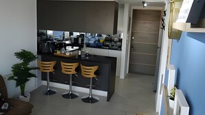 A modern kitchen with a central island, bar stools, and a view of the living area.