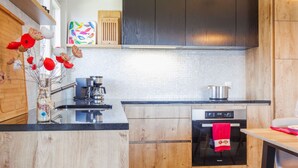 Une cuisine moderne avec des meubles en bois, un plan de travail noir, une machine à café et une cuisinière.