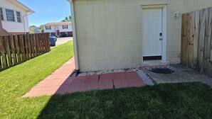 A residential building with a white exterior, a wooden fence, and a red brick pathway leading to a white door. - Modern 1BR Studio in Safe Alexandria Neighborhood , Near Metro & Dining. (Alexandria)