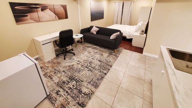 A compact hotel room with a bed, a sofa, a desk, and a small kitchenette. - Modern 1BR Studio in Safe Alexandria Neighborhood , Near Metro & Dining. (Alexandria)