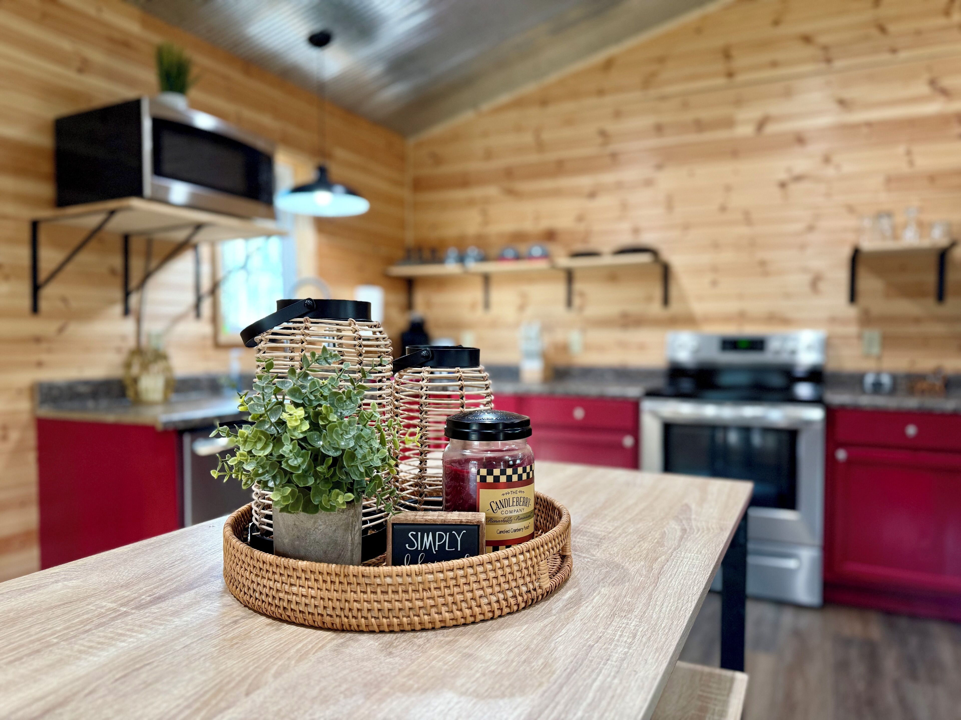 A kitchen with wooden walls, a red countertop, and a woven basket containing jars and a potted plant.