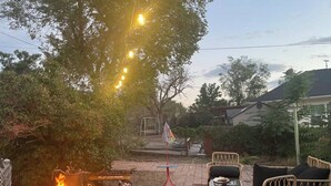 An outdoor patio area with a fire pit, wicker furniture, and a wheelbarrow. - Peach Place (McGill)