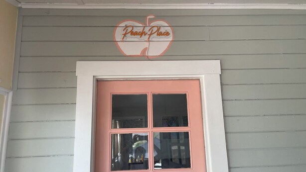A pink door with a heart-shaped sign above it reading "Beach Place". - Peach Place (McGill)
