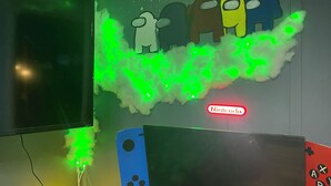A gaming setup with a Nintendo sign, a wall with colorful character cutouts, and two gaming consoles. - Peach Place (McGill)
