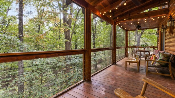 A wooden deck with a table and chairs, overlooking a forested area. - Walk to Lake Blue Ridge | Hot Tub + Fire Pit (Morganton)