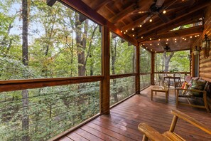 Une terrasse en bois avec une table et des chaises, donnant sur une zone boisée.
